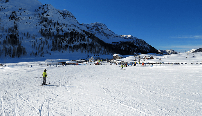 Op wintersport in skigebied San Pellegrino. De blauwe Fuchiade-piste komt uit bij de dalliften en de kapel van San Pellegrino. © SkigebiedenGids.nl